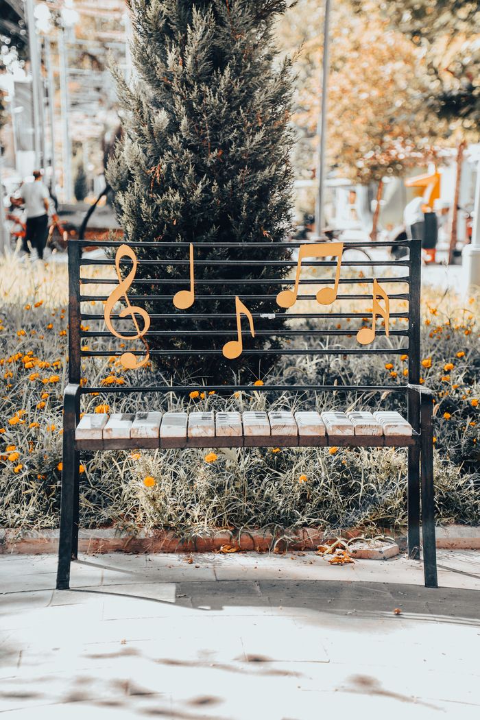 Home Decorative park bench adorned with musical notes in a serene outdoor setting.